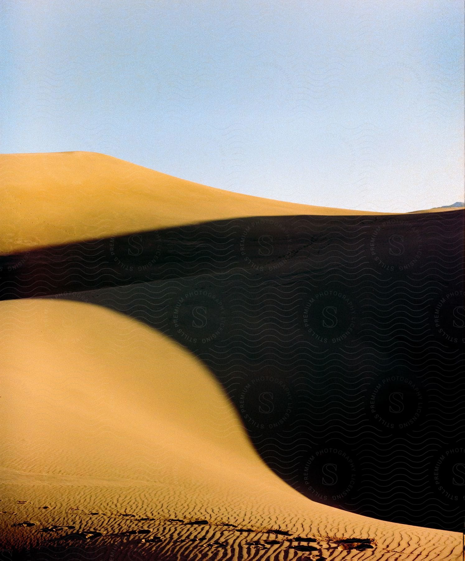 A sand dune casts a shadow on the desert below