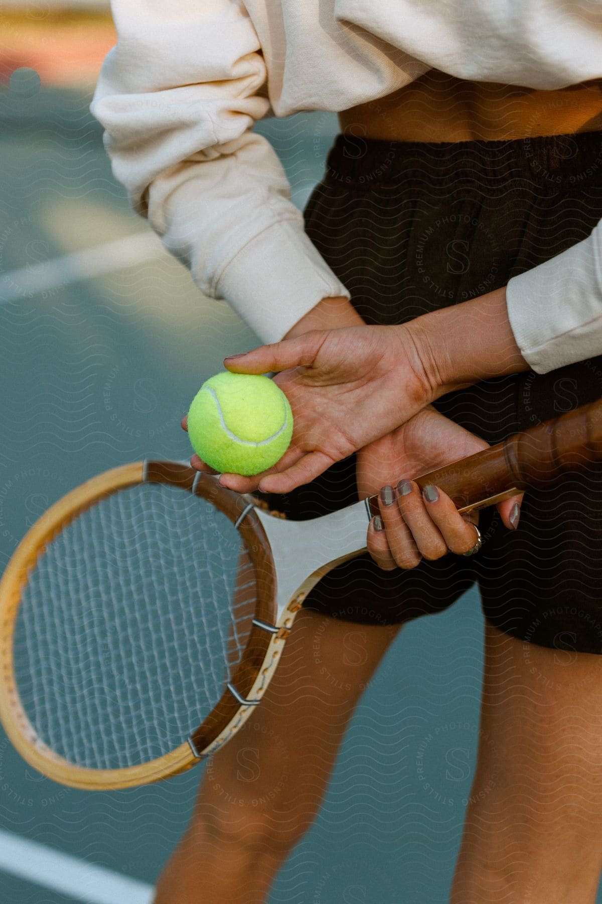 A woman holds a tennis ball in one hand and a racket in the other