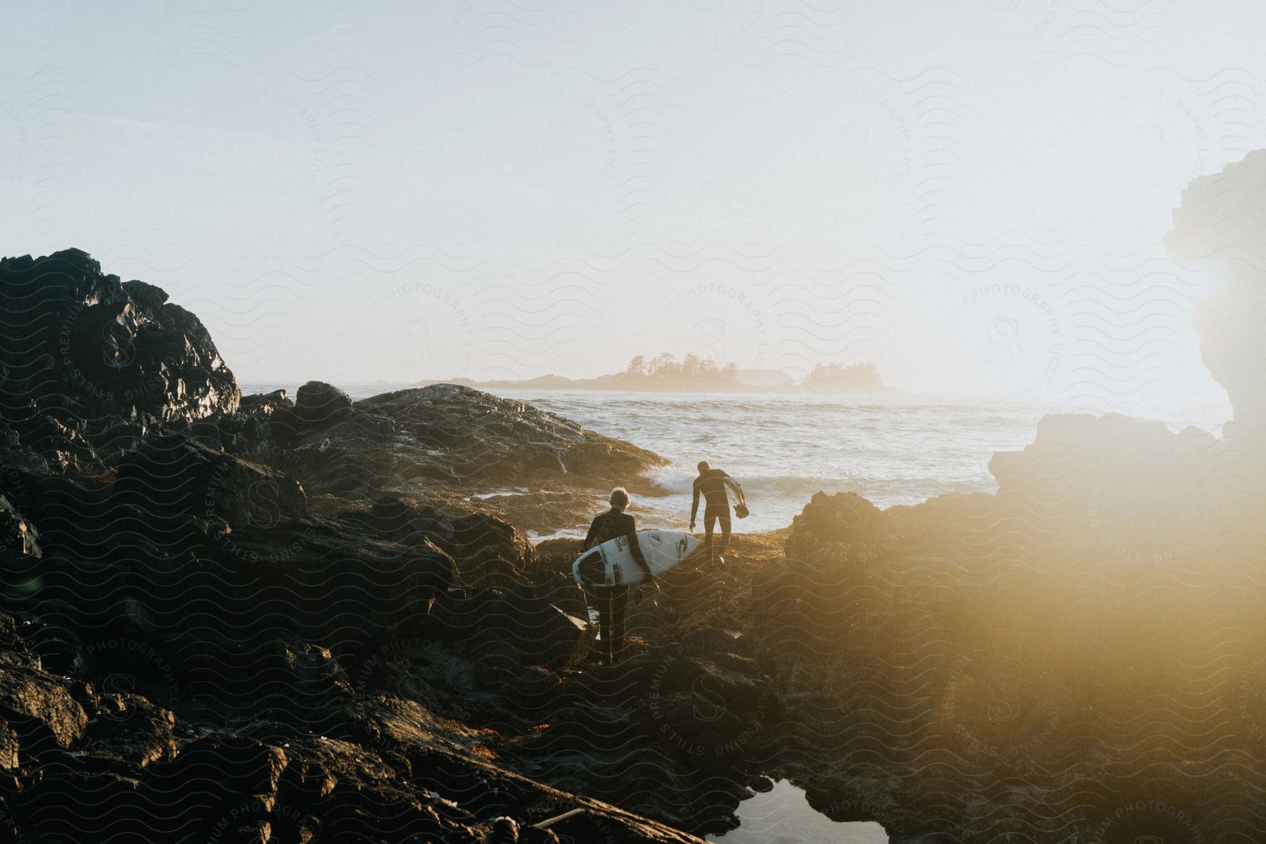 Two people holding surf boards walking toward the ocean on a canadian beach