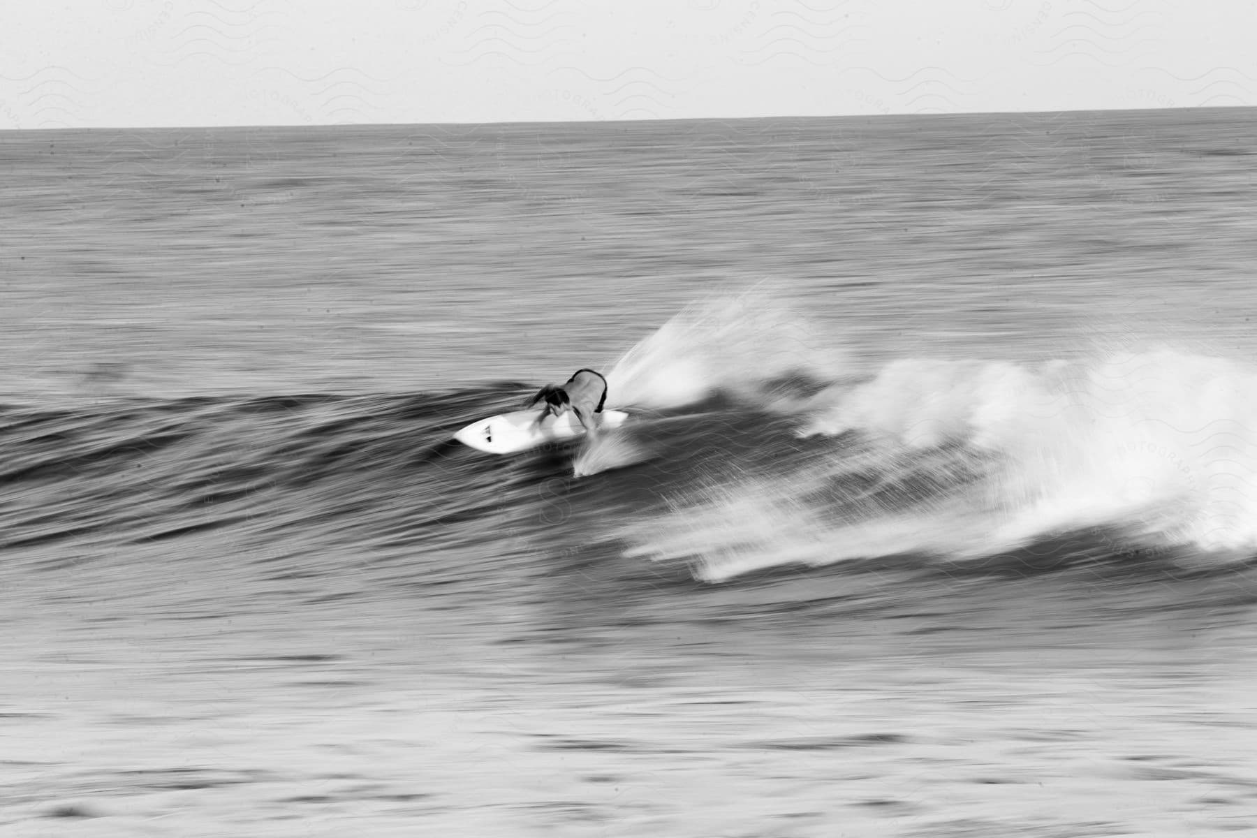 A man surfs on a wave in black and white