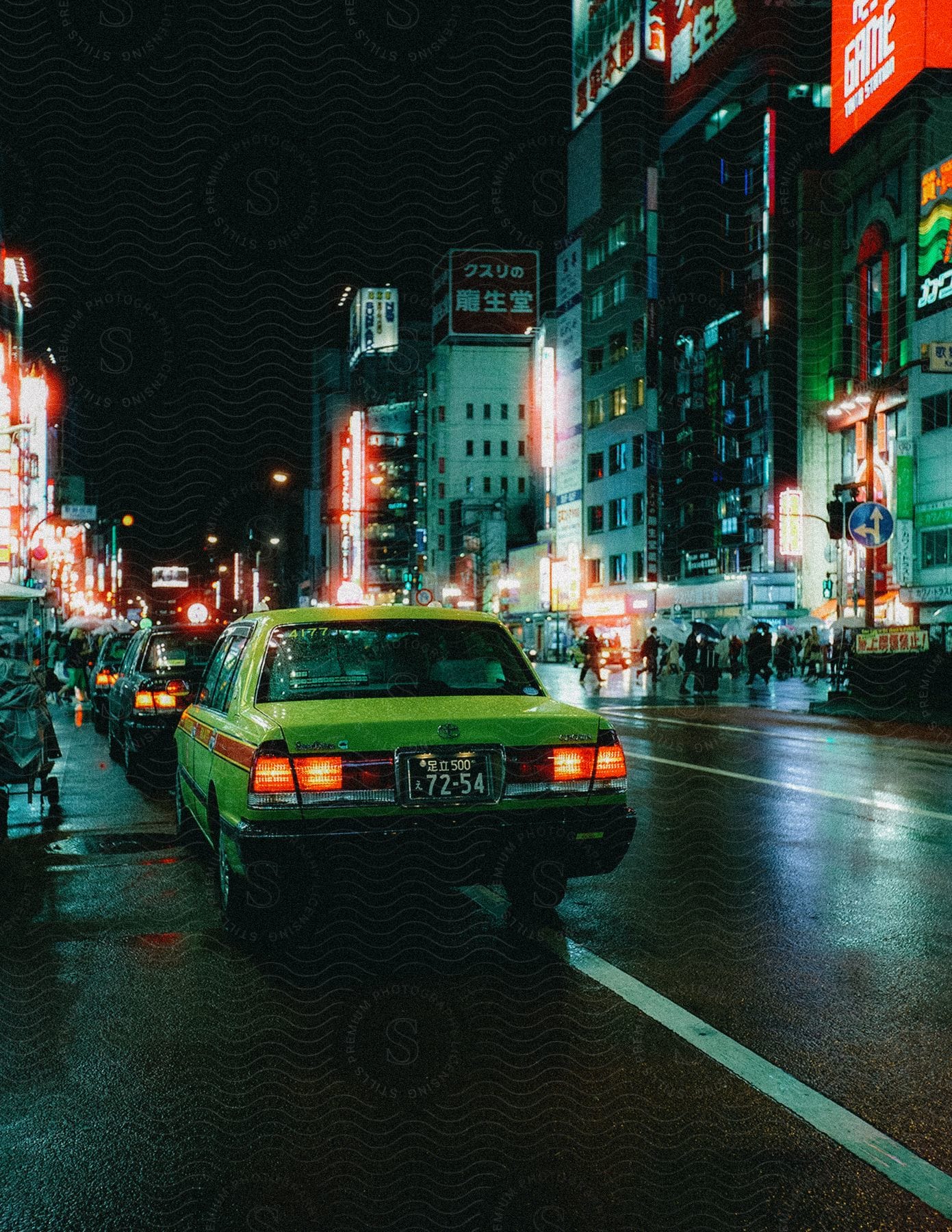 A busy asian city at night with cars and people on the roads and sidewalks