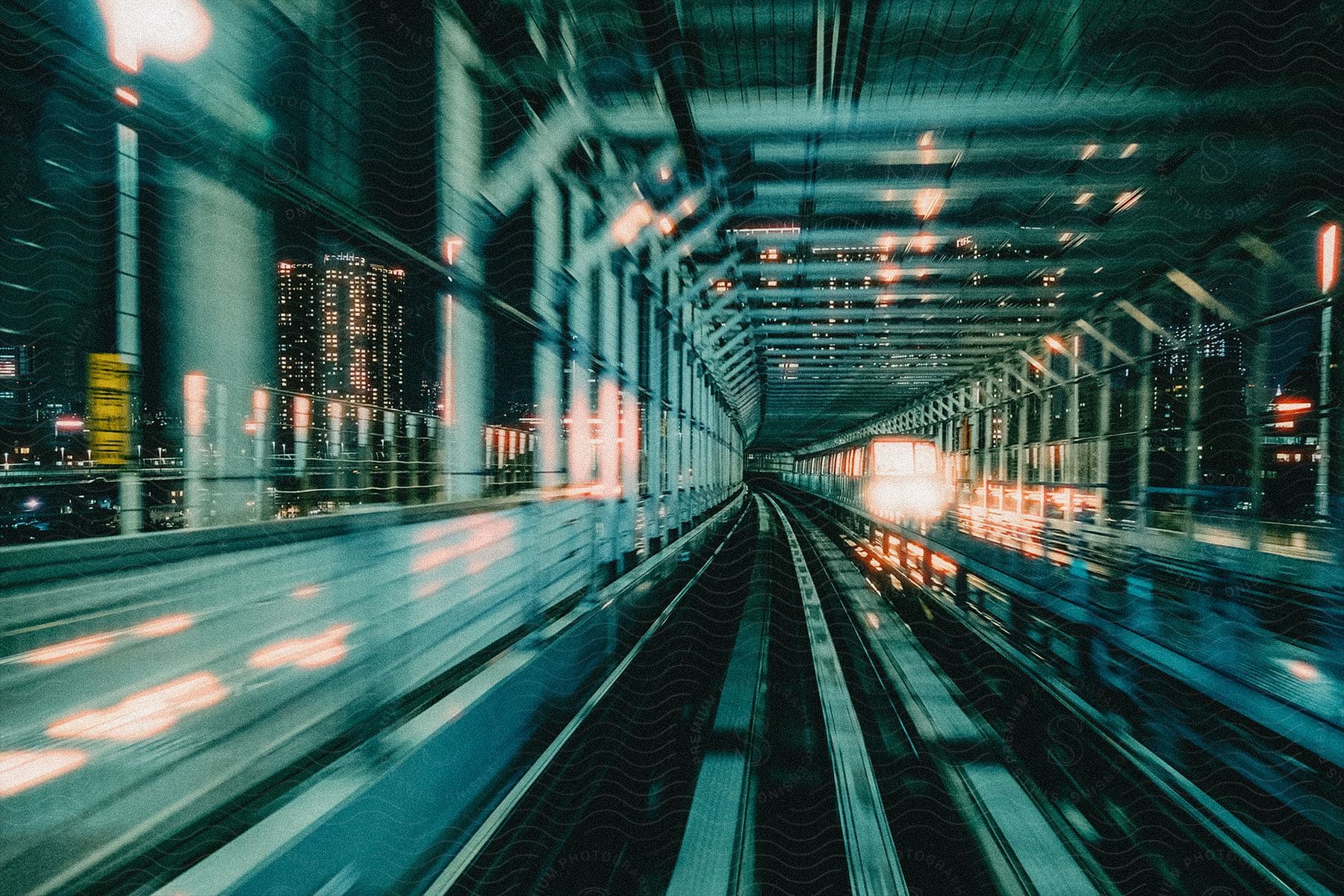 A brightly lit subway train moving through a city at night