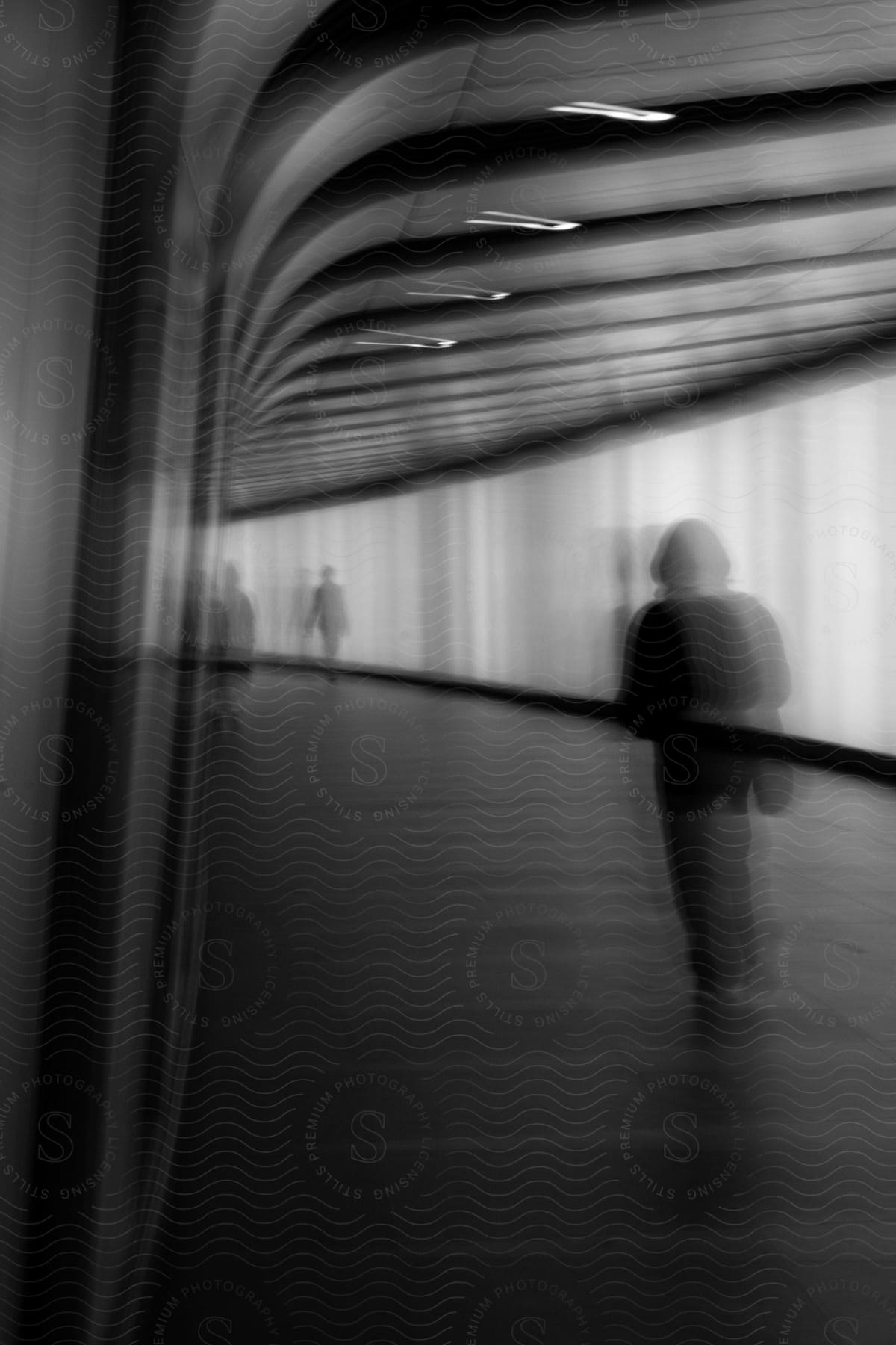 Silhouettes of people walking on a long corridor inside a building