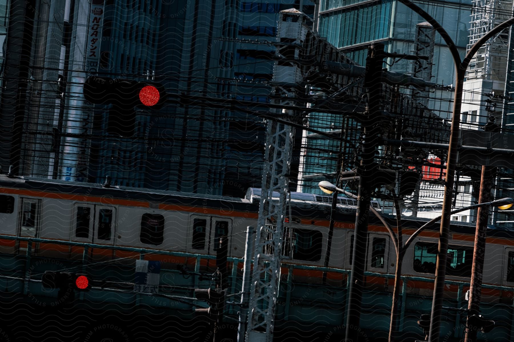 A train travels through a cityscape of tall buildings traffic lights power lines and another train on the tracks