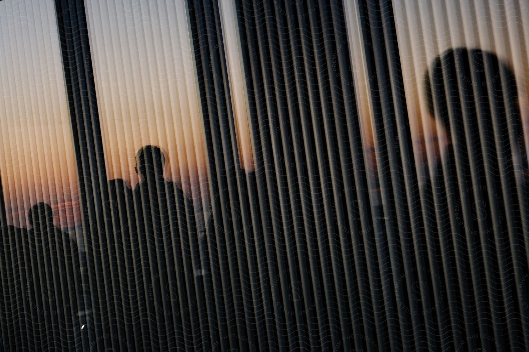 Three men standing in front of an office building window with their silhouettes reflected in the glass