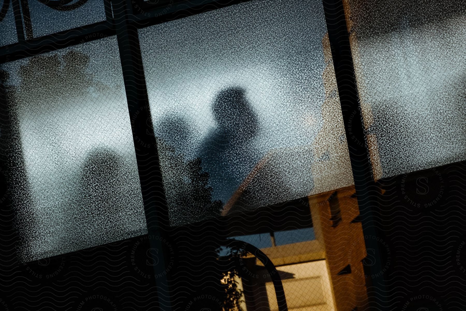 A house with transparent window glass reveals the reflection of people inside the room