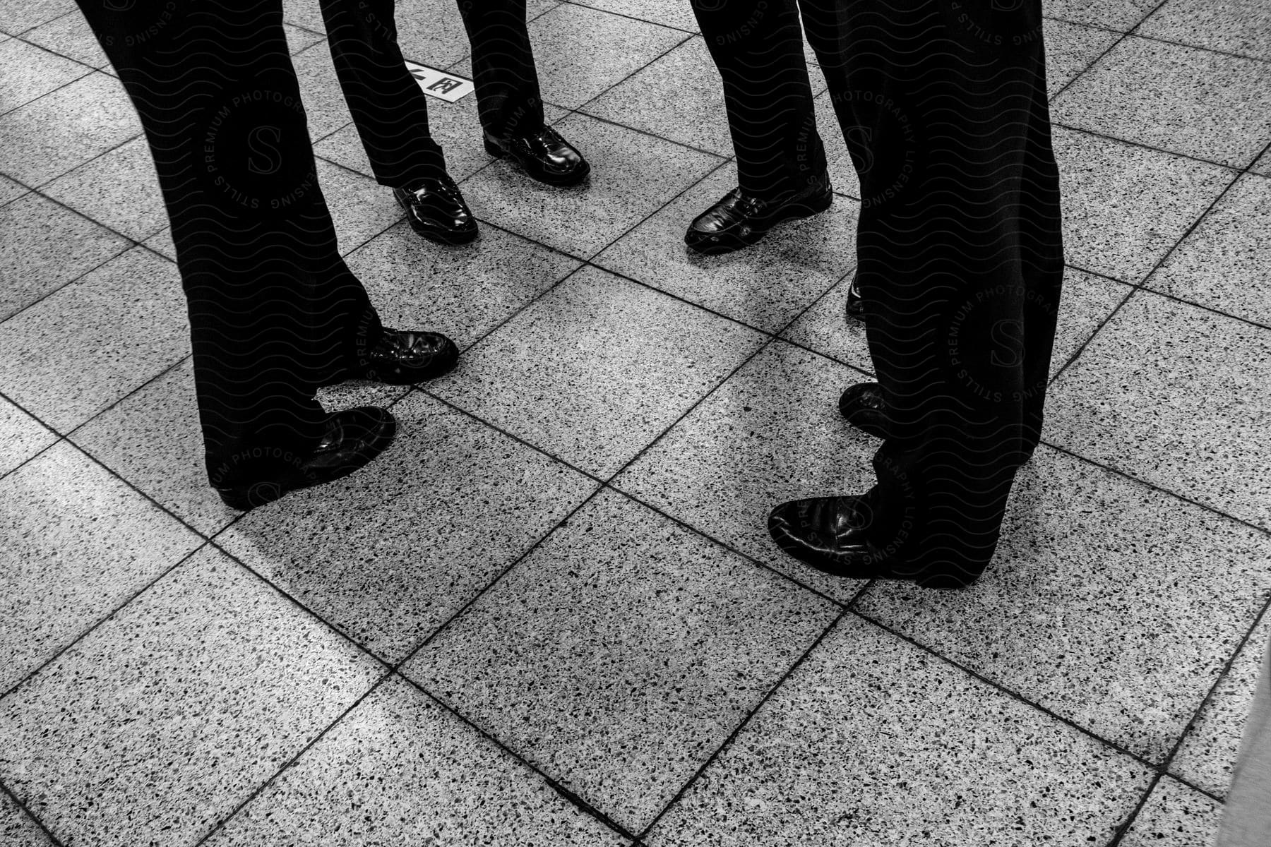 Four men in suits standing on a tiled floor