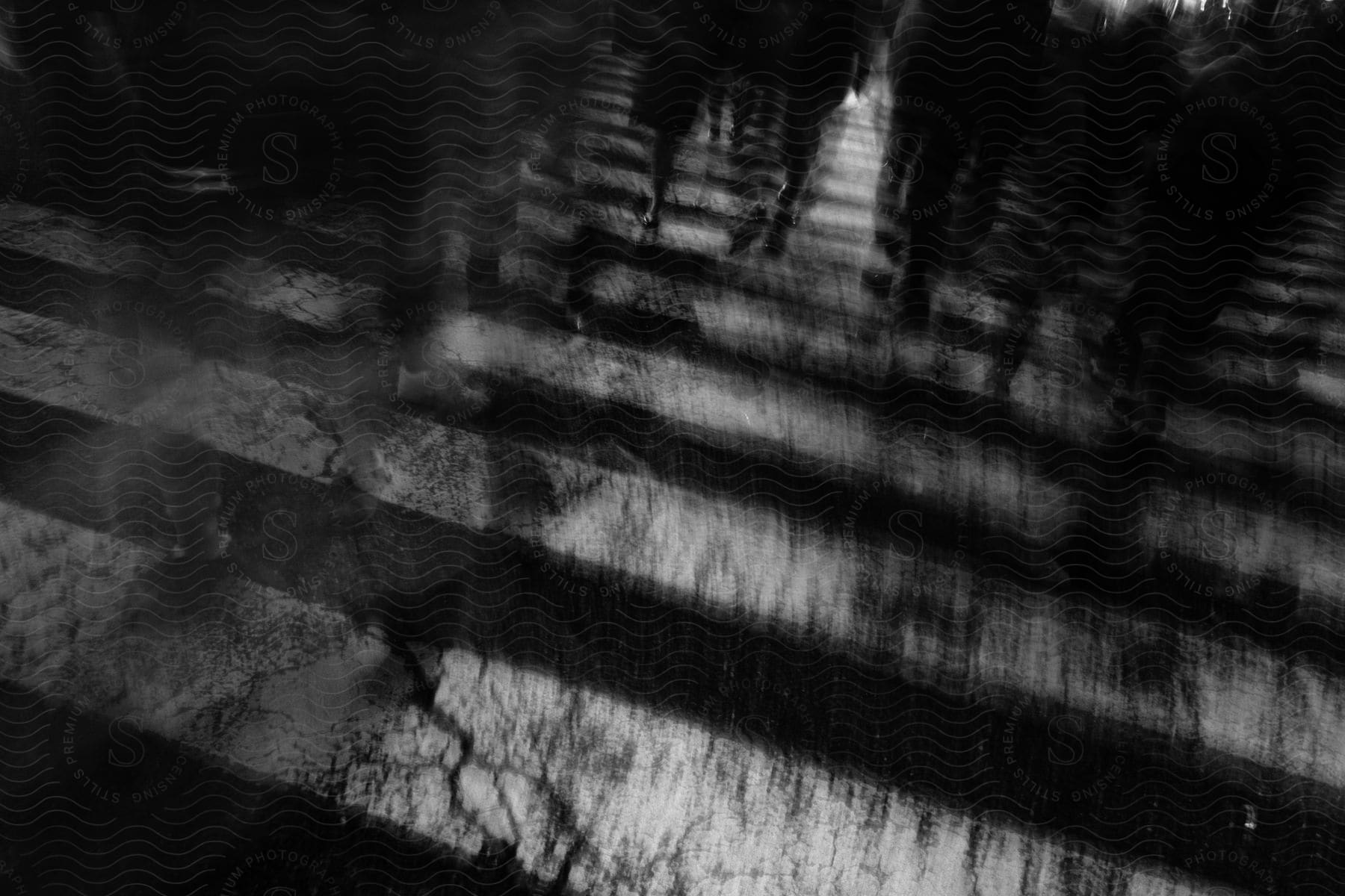 A black and white zebra crossing with people crossing creating movement