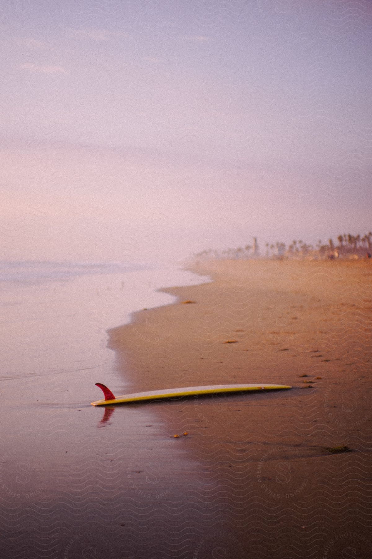 A surfboard on a beach at sunrise