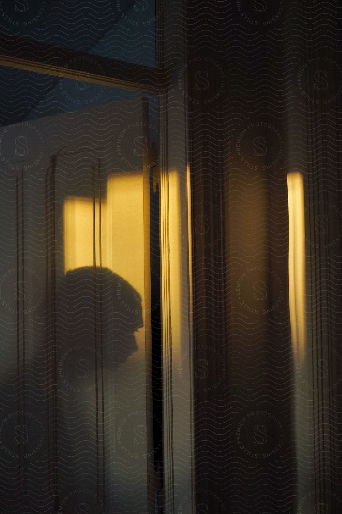 A person standing in a welllit room with wooden flooring and a door in the background