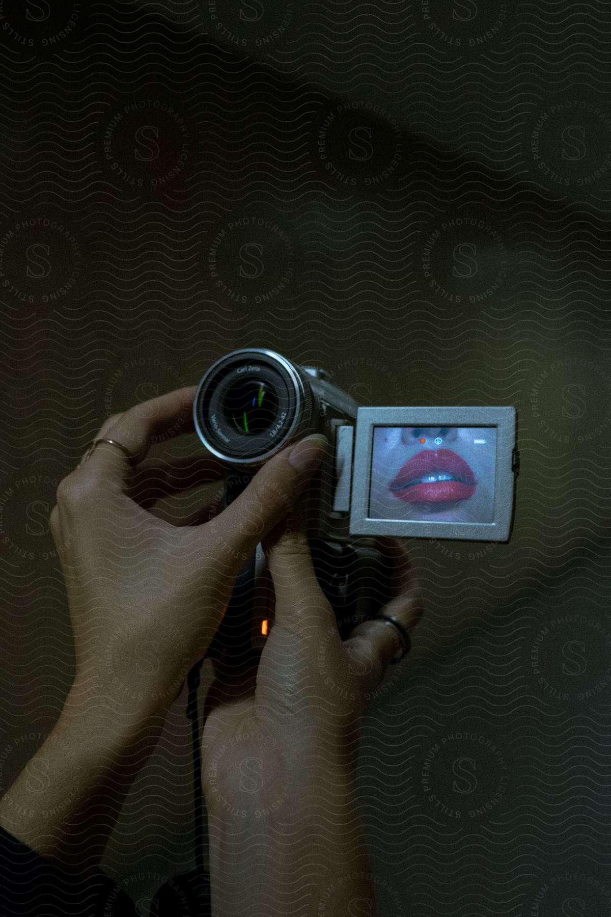 A woman holding a camcorder with red lipstick on her lips