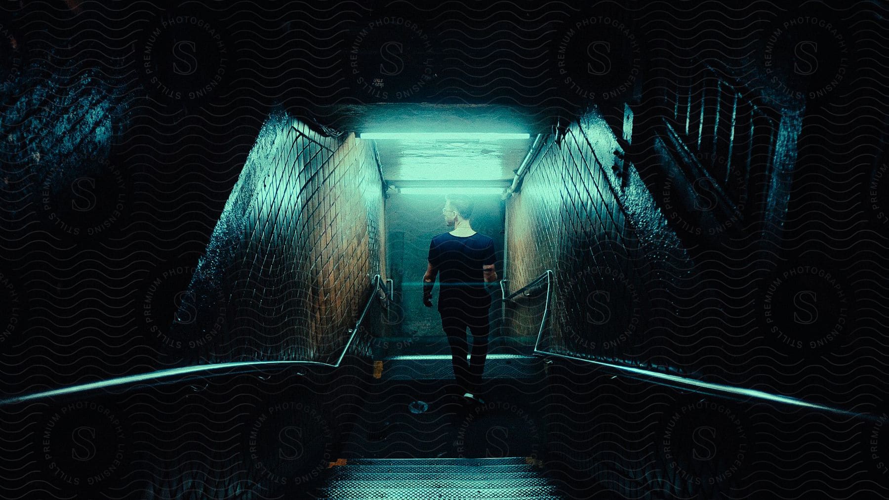 A man descending stairs into an underground passage at night in new york city