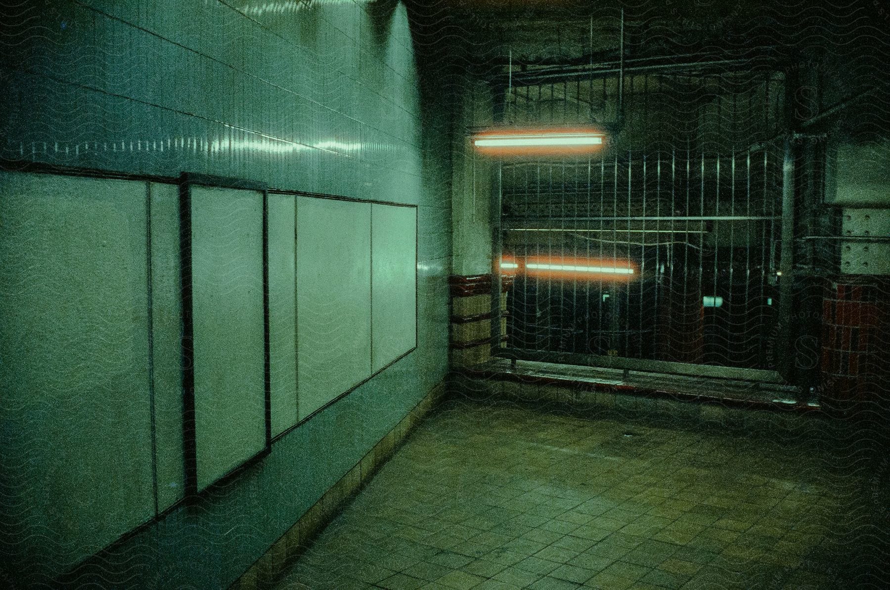 An underground empty facility with a white board on the wall fluorescent light and steel gate