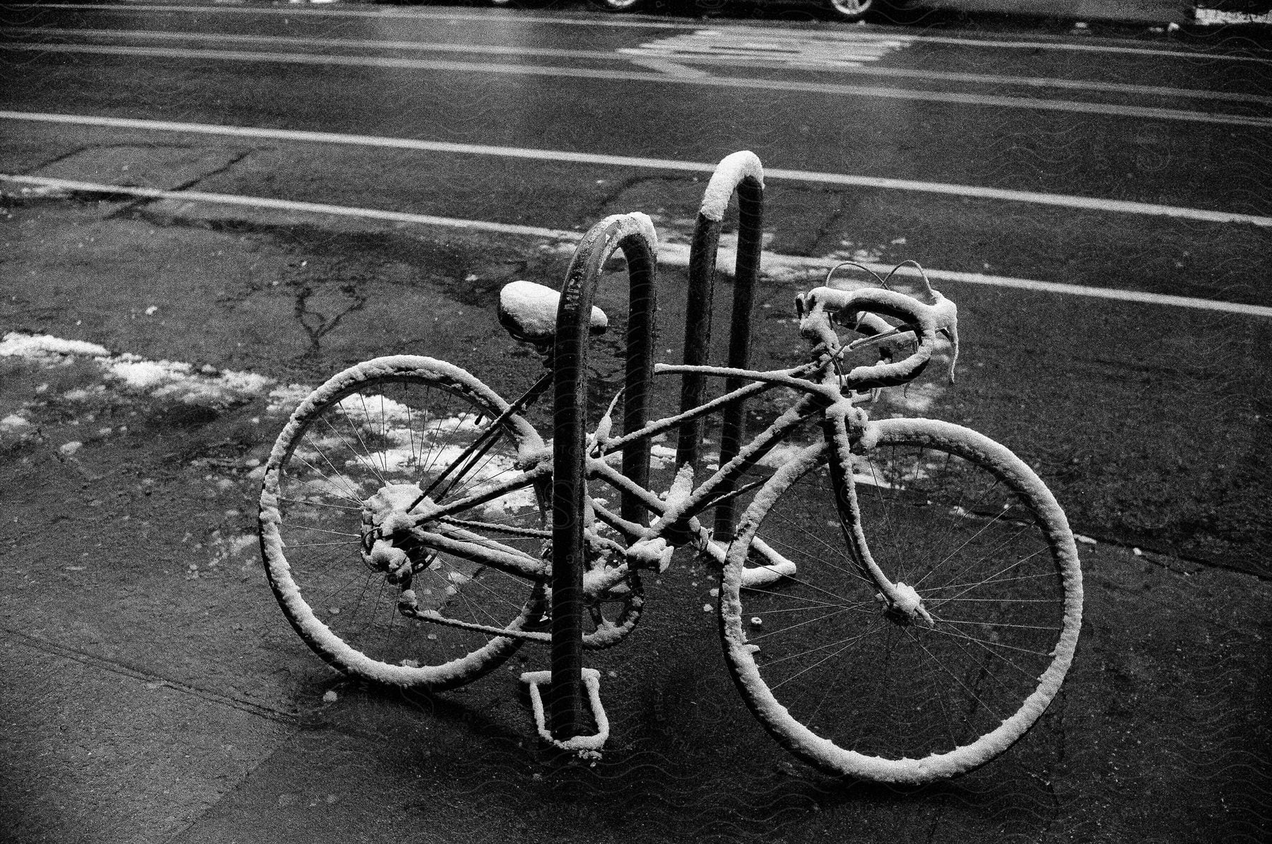 A bicycle covered in ice and snow parked on a downtown curb