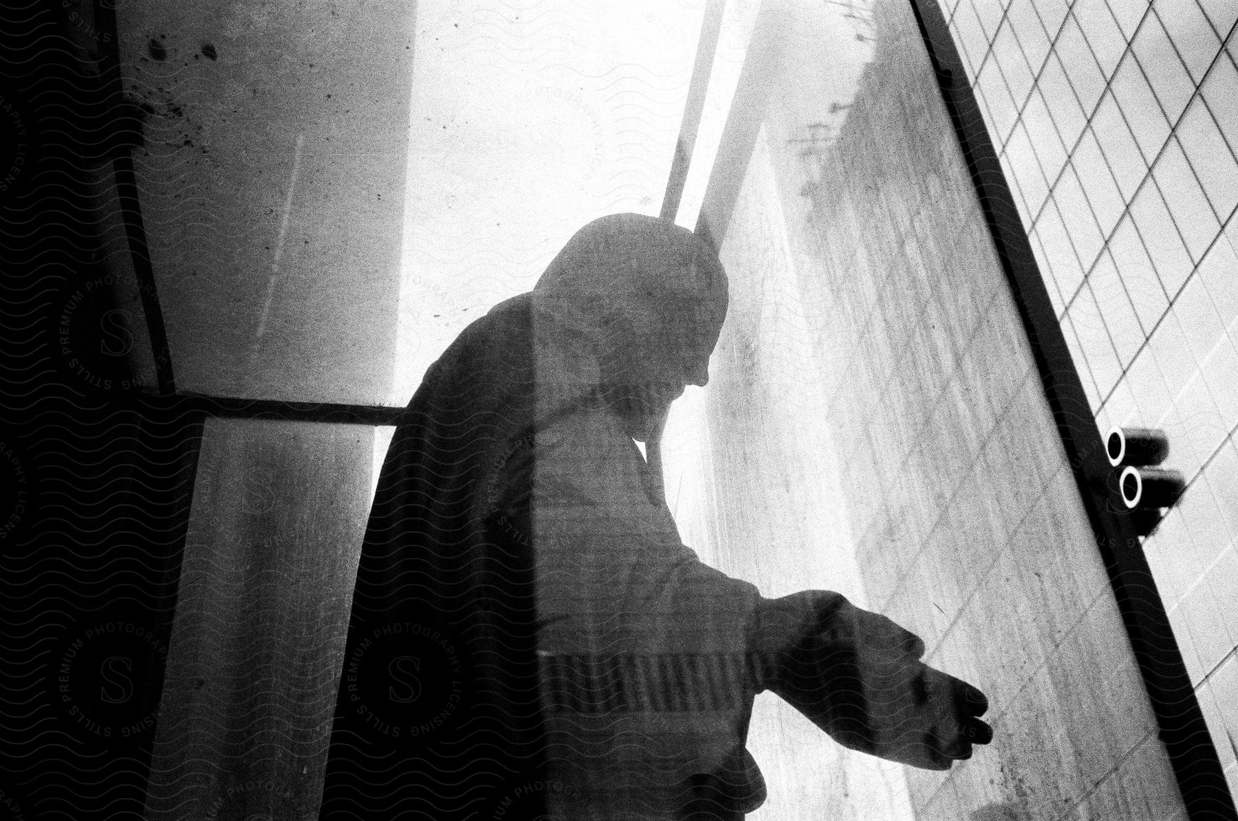 A black and white photo of a religious statue in a glass box with open hands reflecting a wall