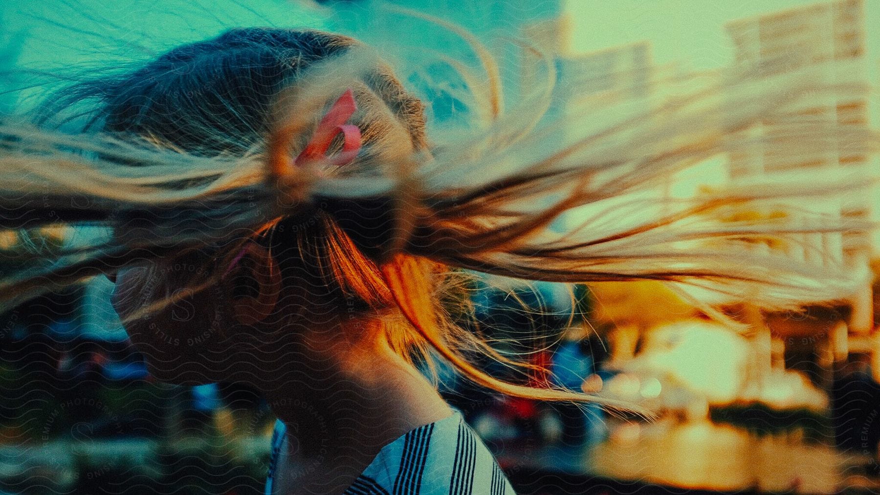 A girl with windblown hair in a city on a sunny day