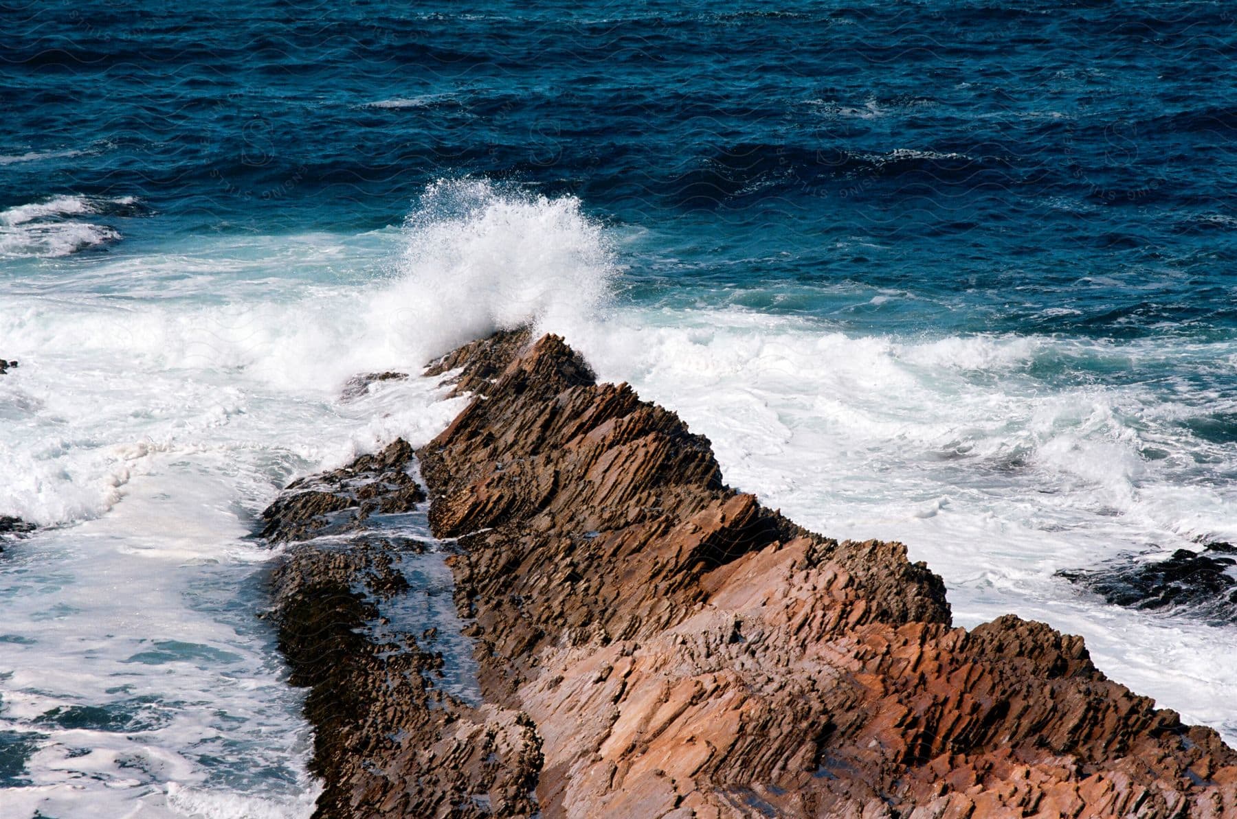 Sea waves breaking on coastal rocks during the day