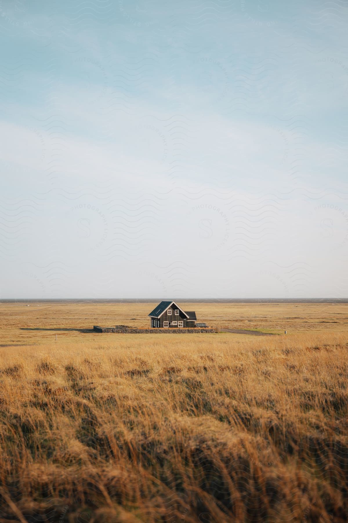 A house surrounded by grass and wheat fields with grassy plains in the background