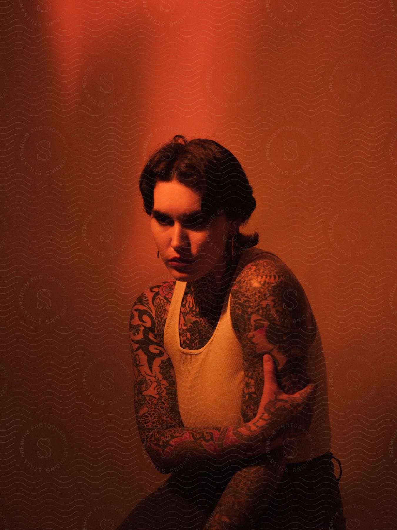 A woman with tattoos sitting on a stool in a red room