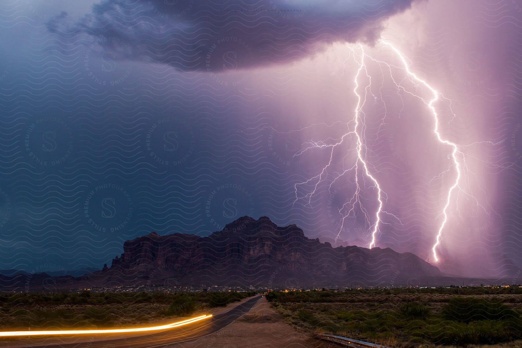 Lightning strikes a rocky hill during a thunderstorm over a city