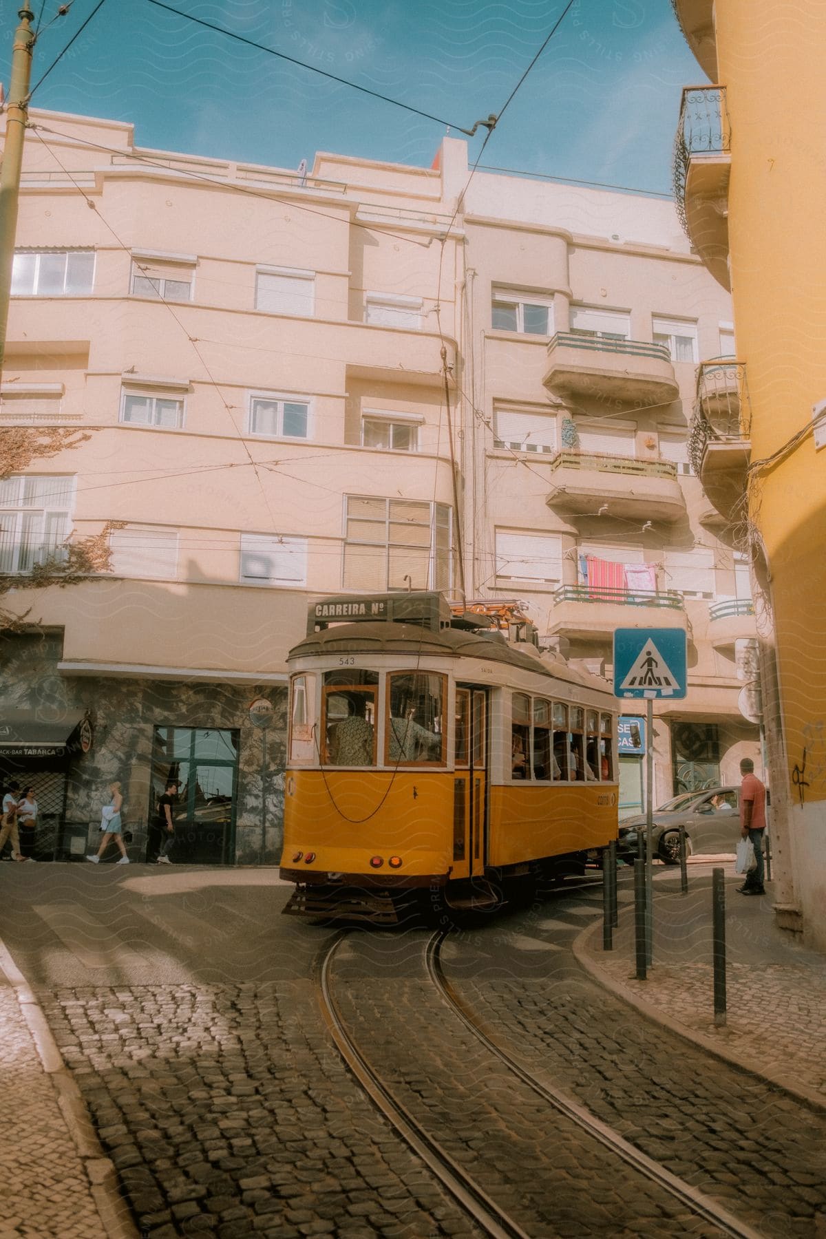 A yellow railcar is driving around the city with many people onboard