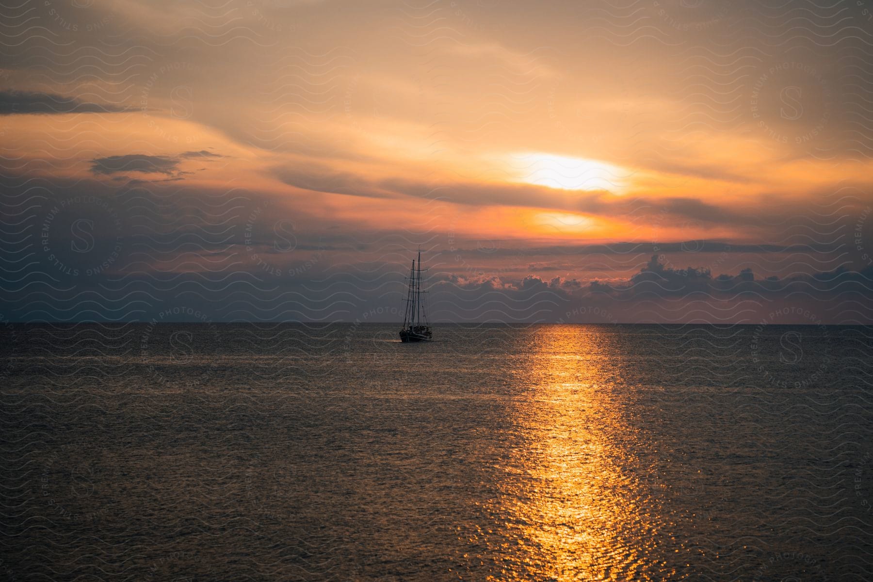 A boat is floating on calm ocean water during a sunset evening