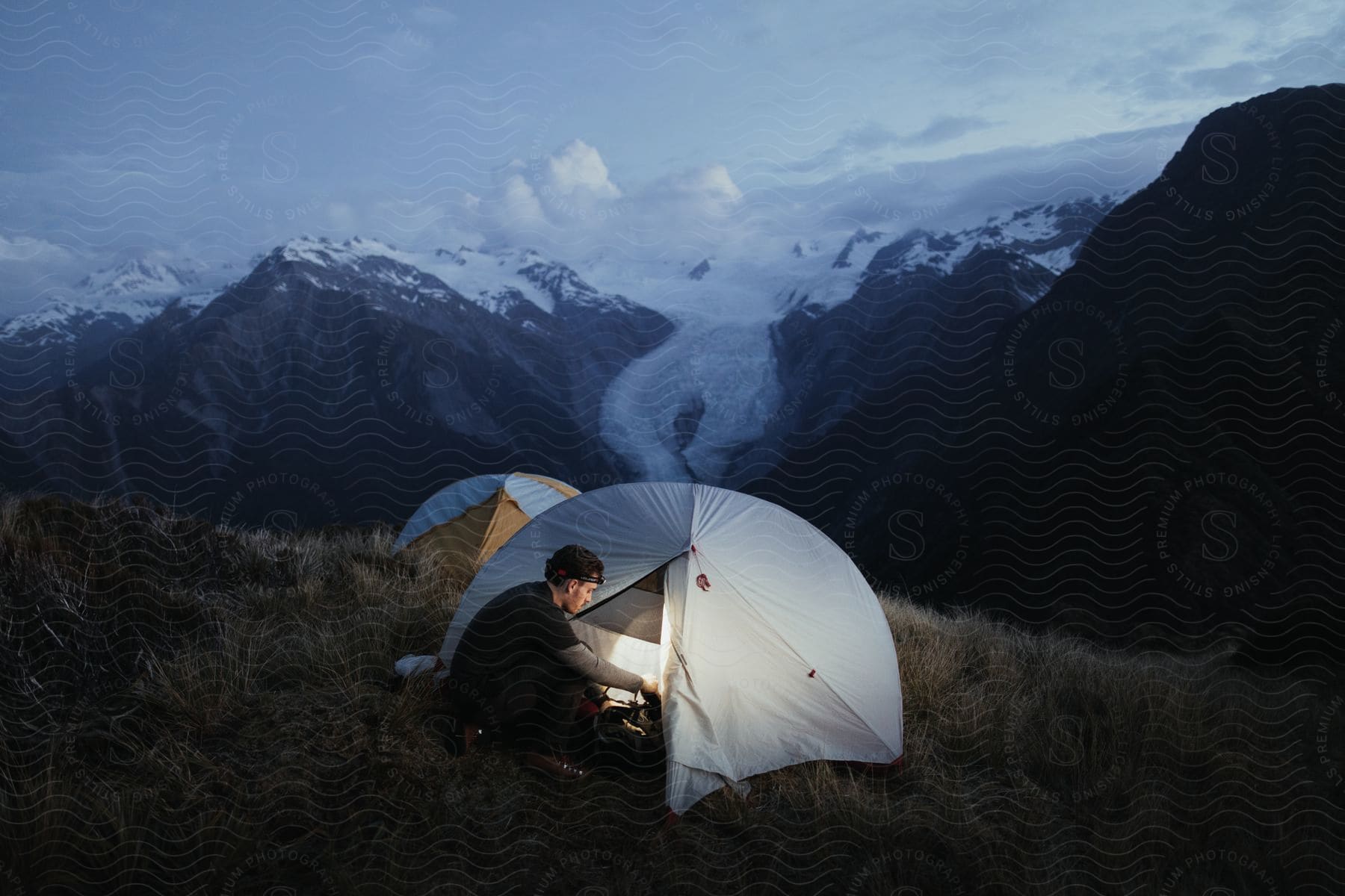 A man camping in the mountains at dusk or dawn