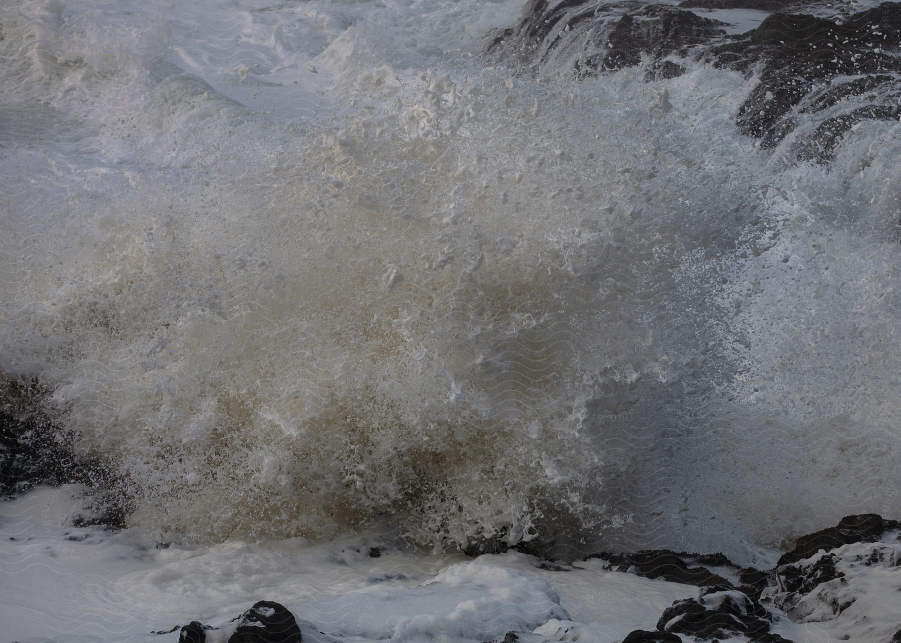 Waves crash against snowy coastal rocks