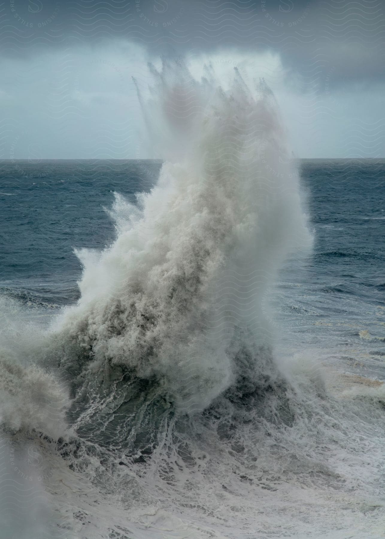 Water splashing high as a wave crashes against a rock