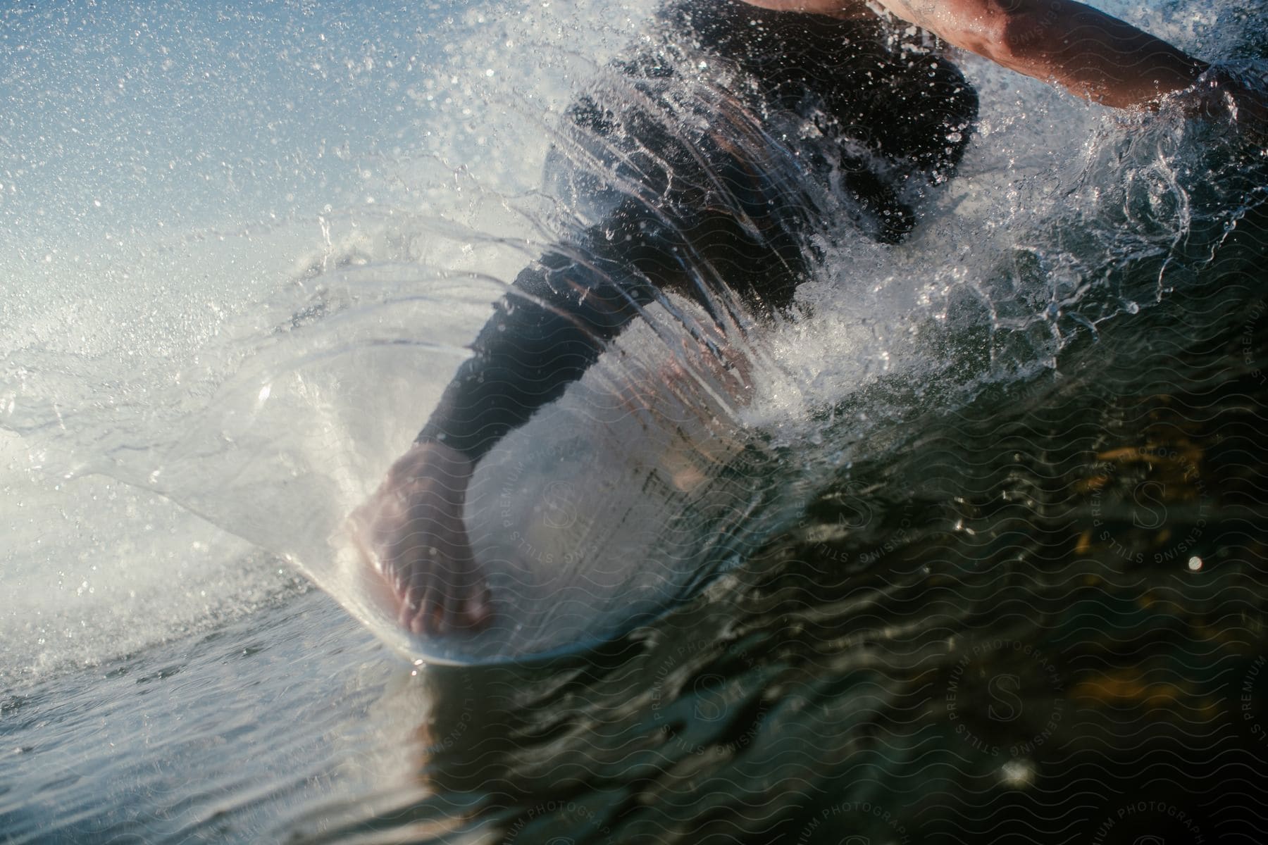 A surfer cuts through a wave and kicks up spray