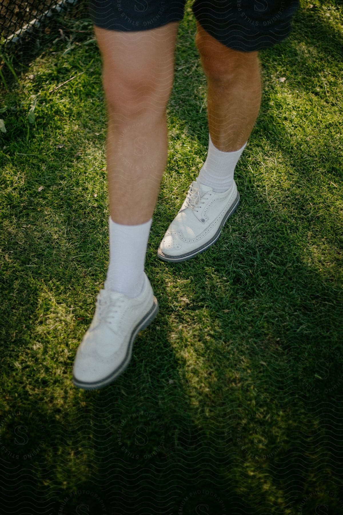 A man is wearing black shorts with tall white socks and white shoes