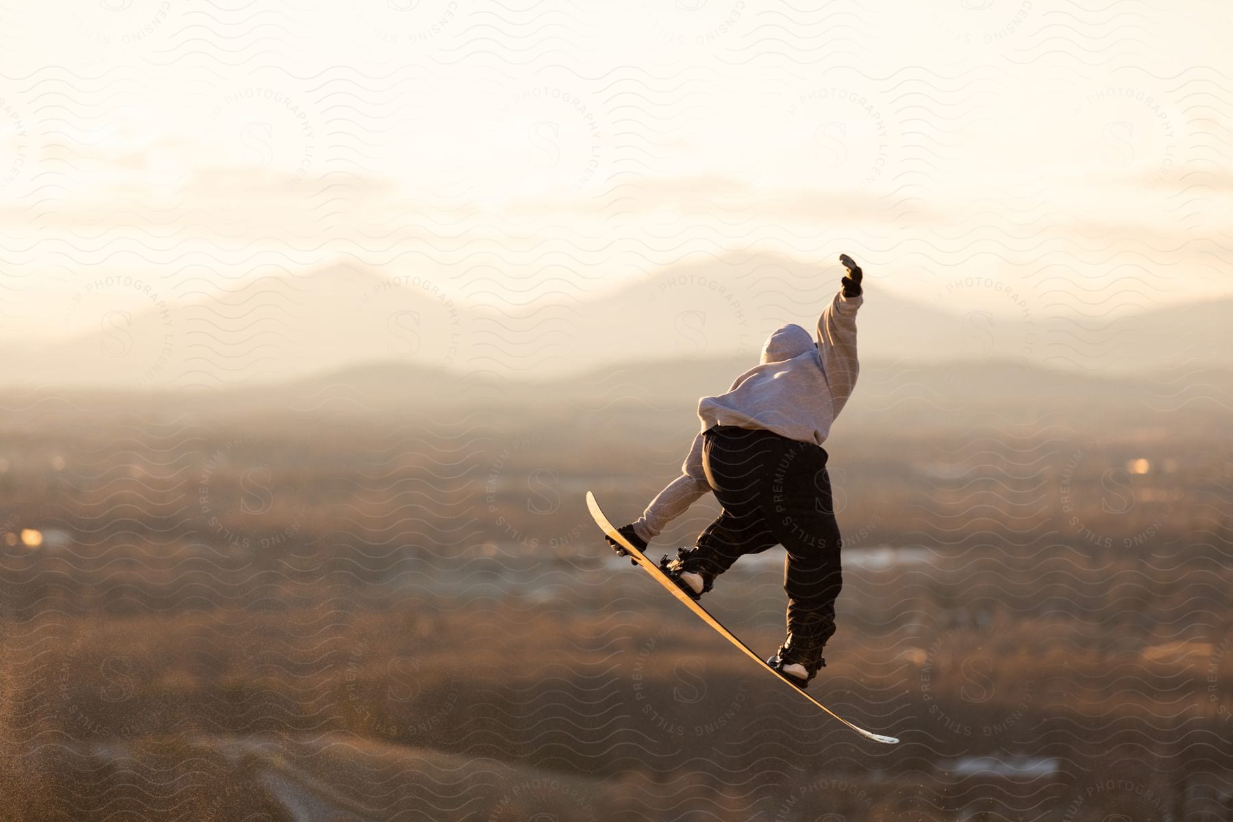 a man on a snowboard up in the air while performing a stunt during spring in an area with a mountain in distance