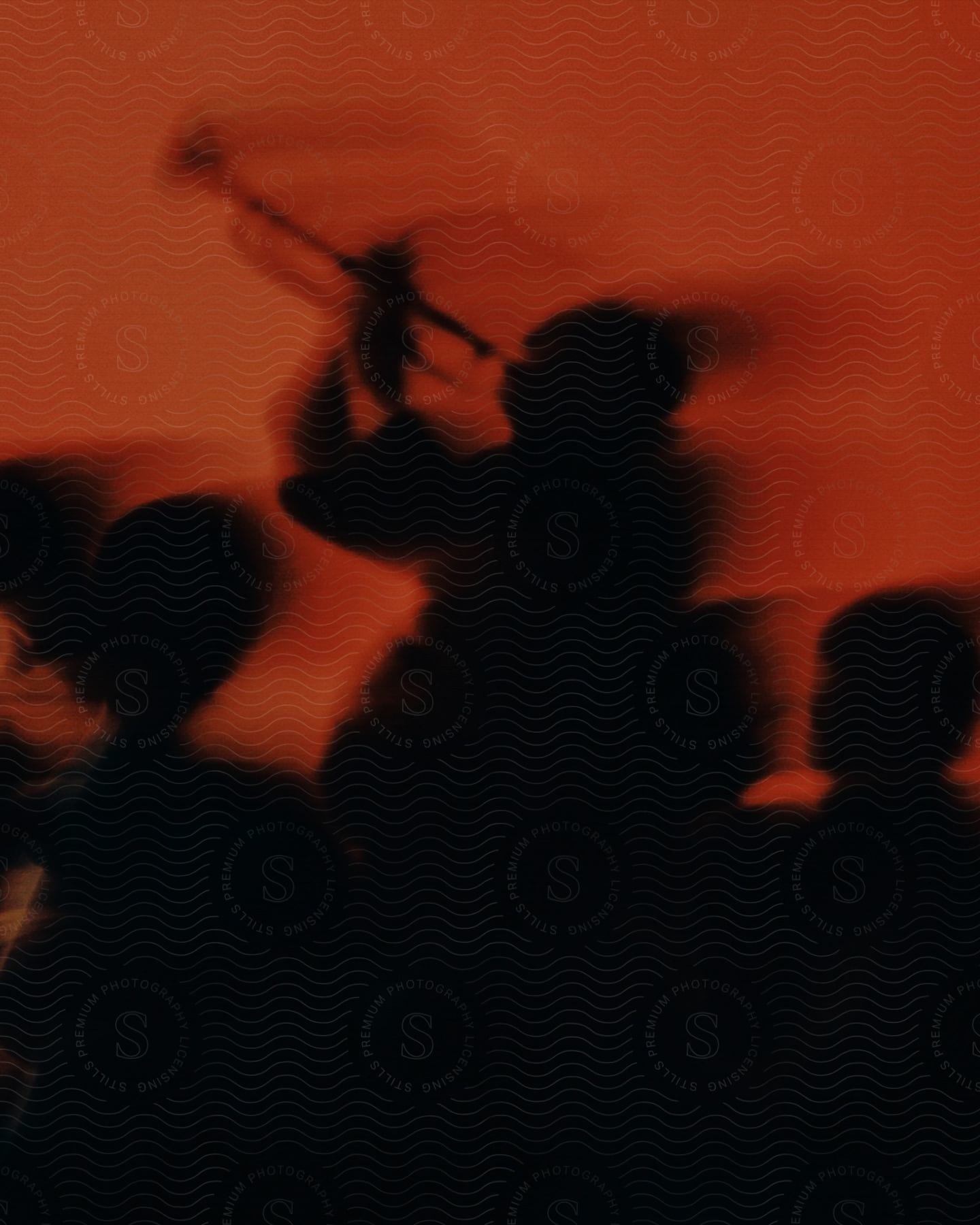 blurred abstract silhouettes of musicians performing against a red background