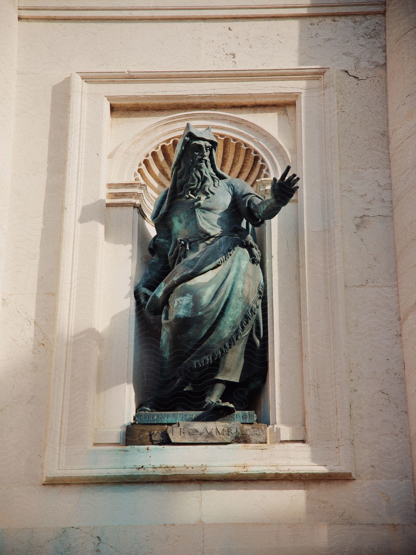 metal statue of a bearded man raising his hand at the outside of a classical style building