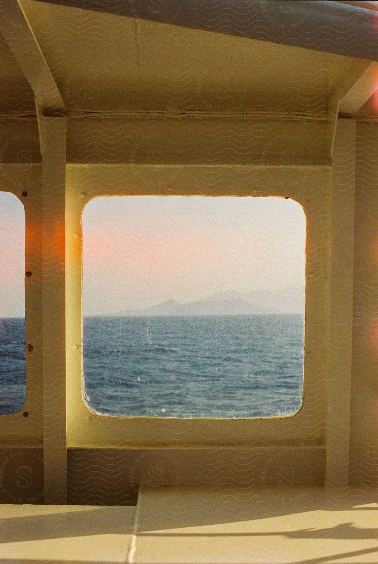 View from inside the boat to a window on a sunny day with the sea in motion.