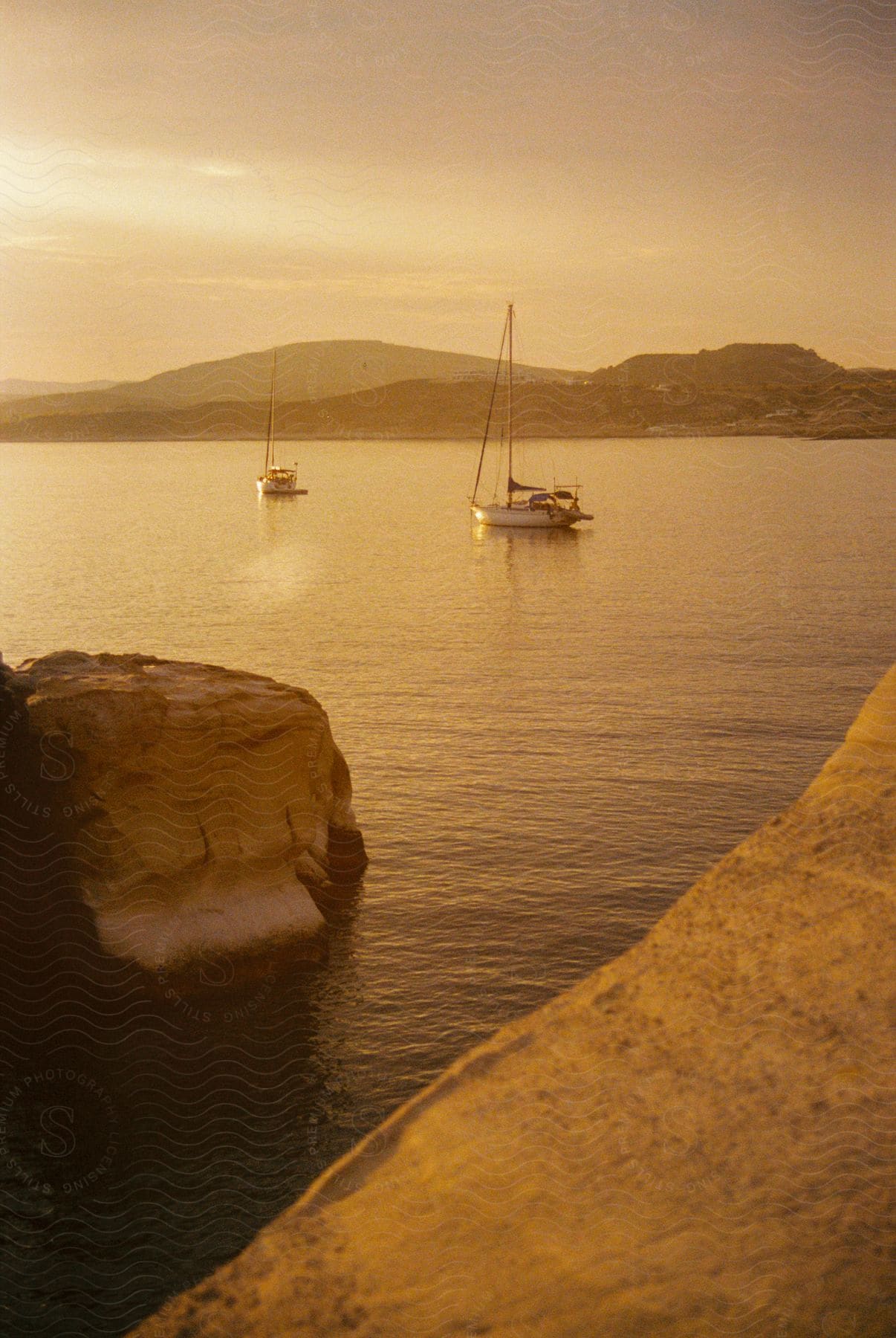 Boats are sailing in water off the coast with mountains in the distance