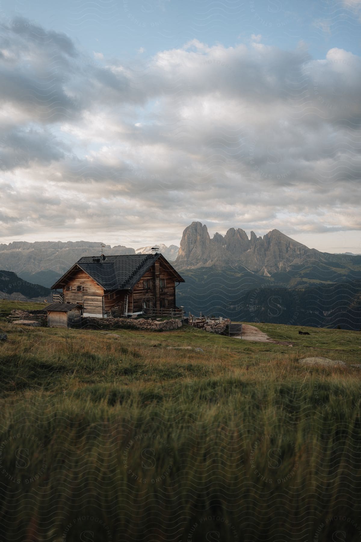 A rural house out in the middle of a mountain area with clouds in the distance