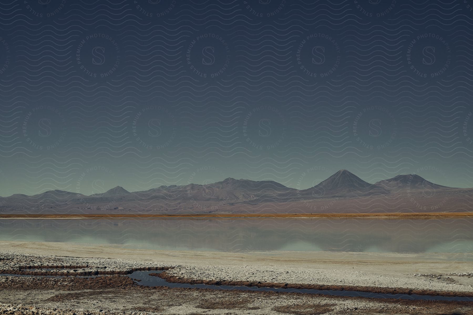 A small body of water situated in front of some sandy hills.