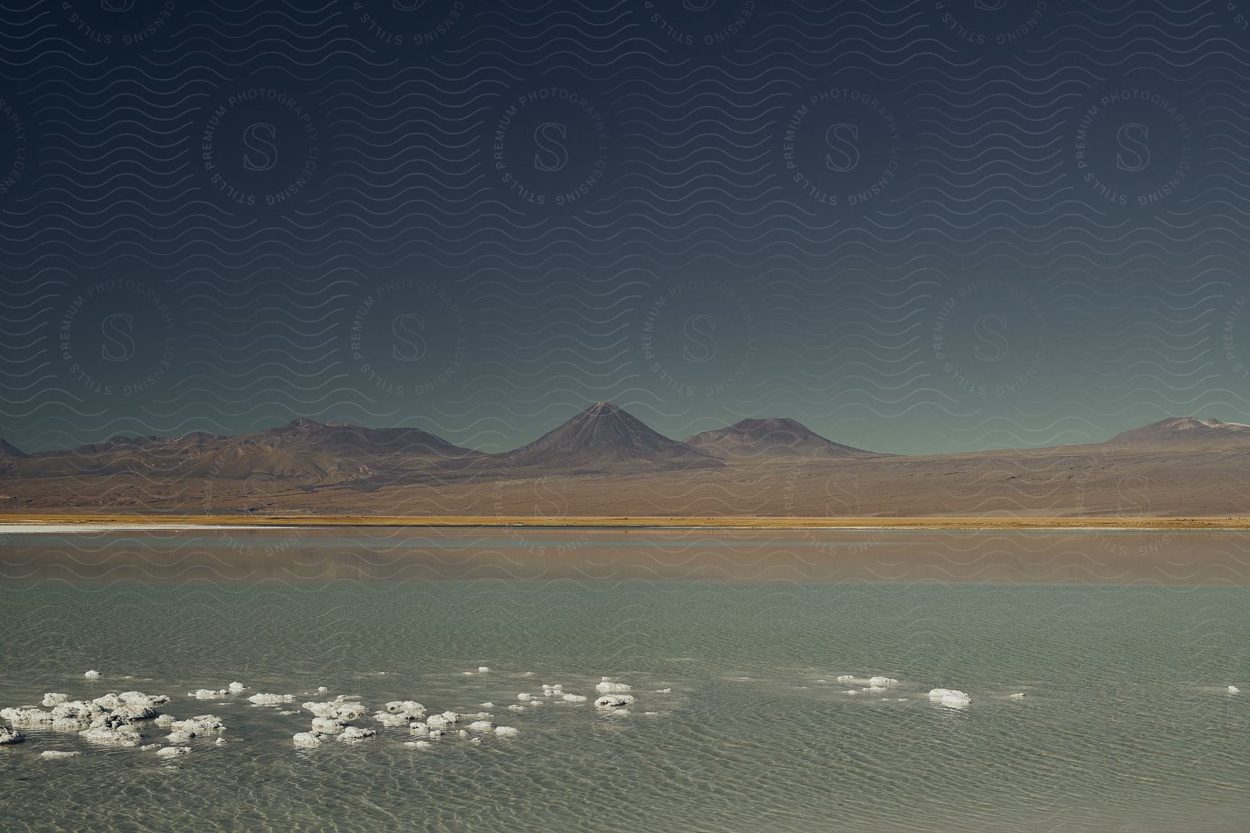 A mountain is setting in the back horizon with a lake in the front.