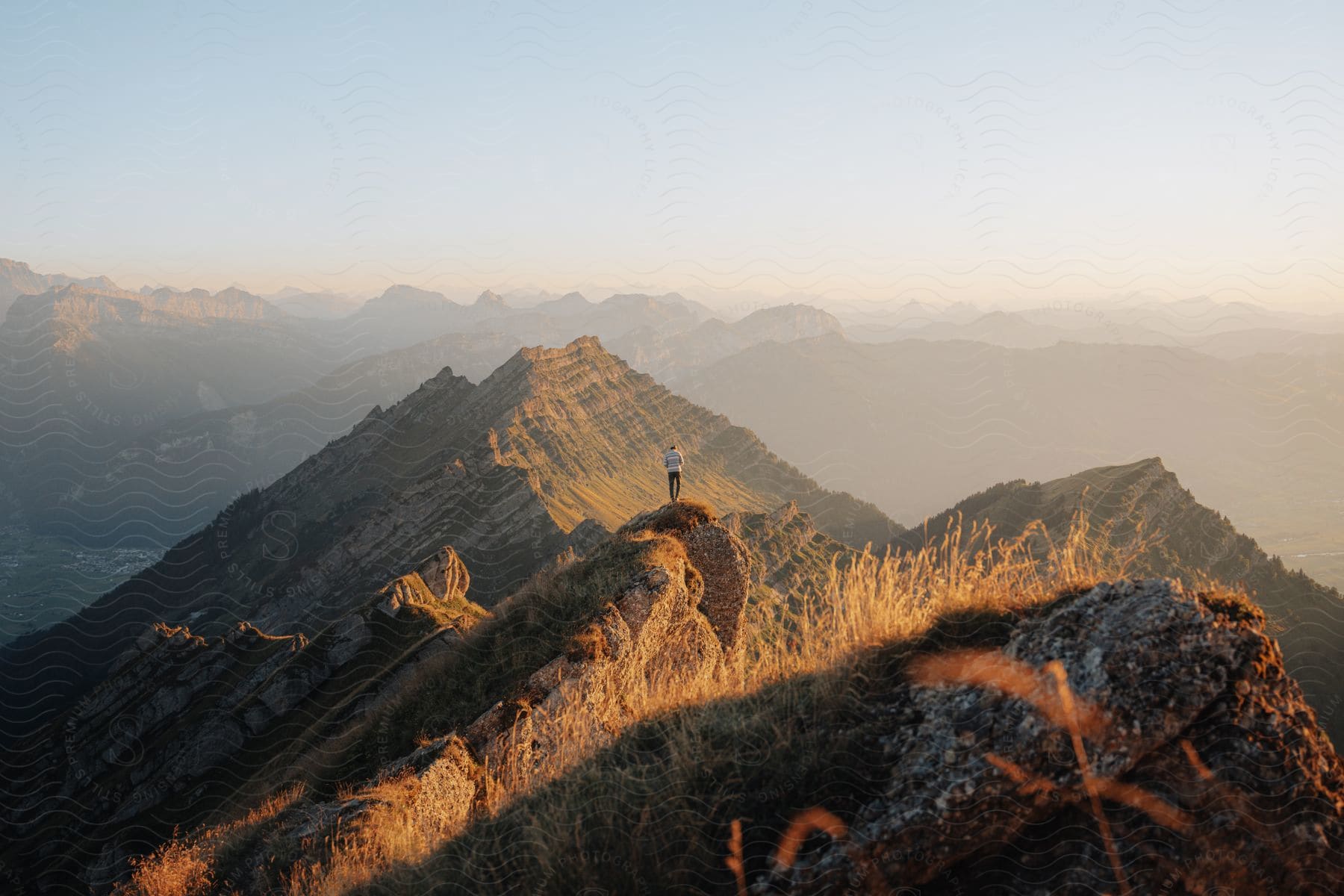 hiking man standing over a rock at the top of a mountain during dusk or dawn