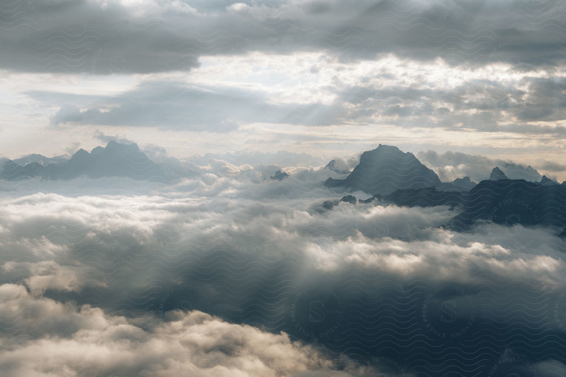 Mountain peaks high above the clouds as rays of sunlight shine from above