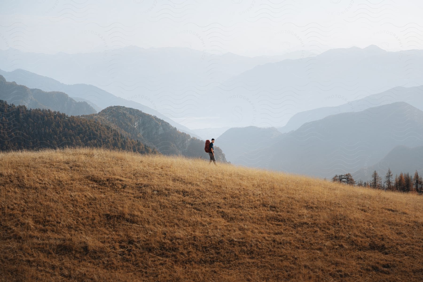 man carrying a backpack hiking at the mountains during day time