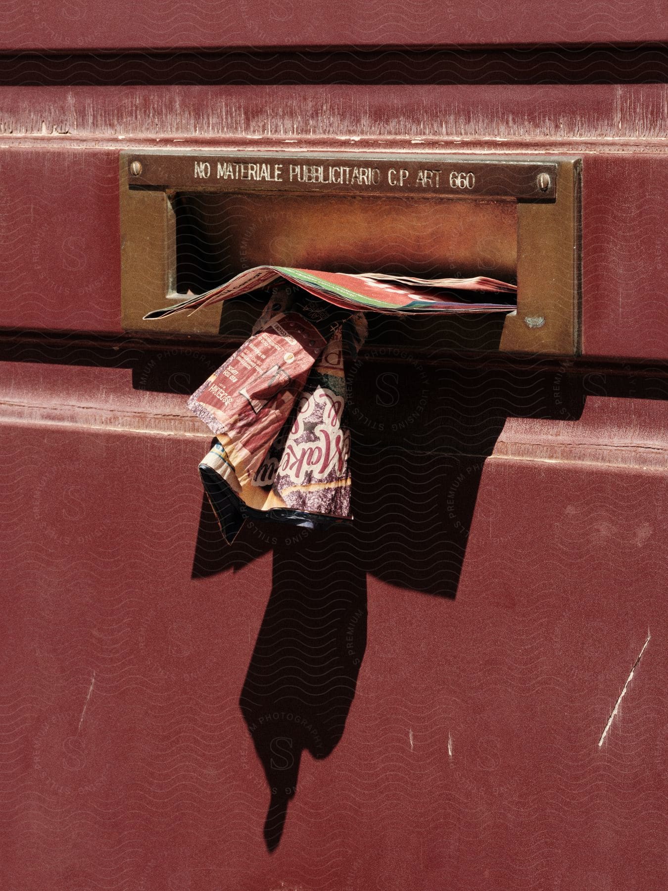 Magazines and illustrations are sticking out of a mail slot on a building