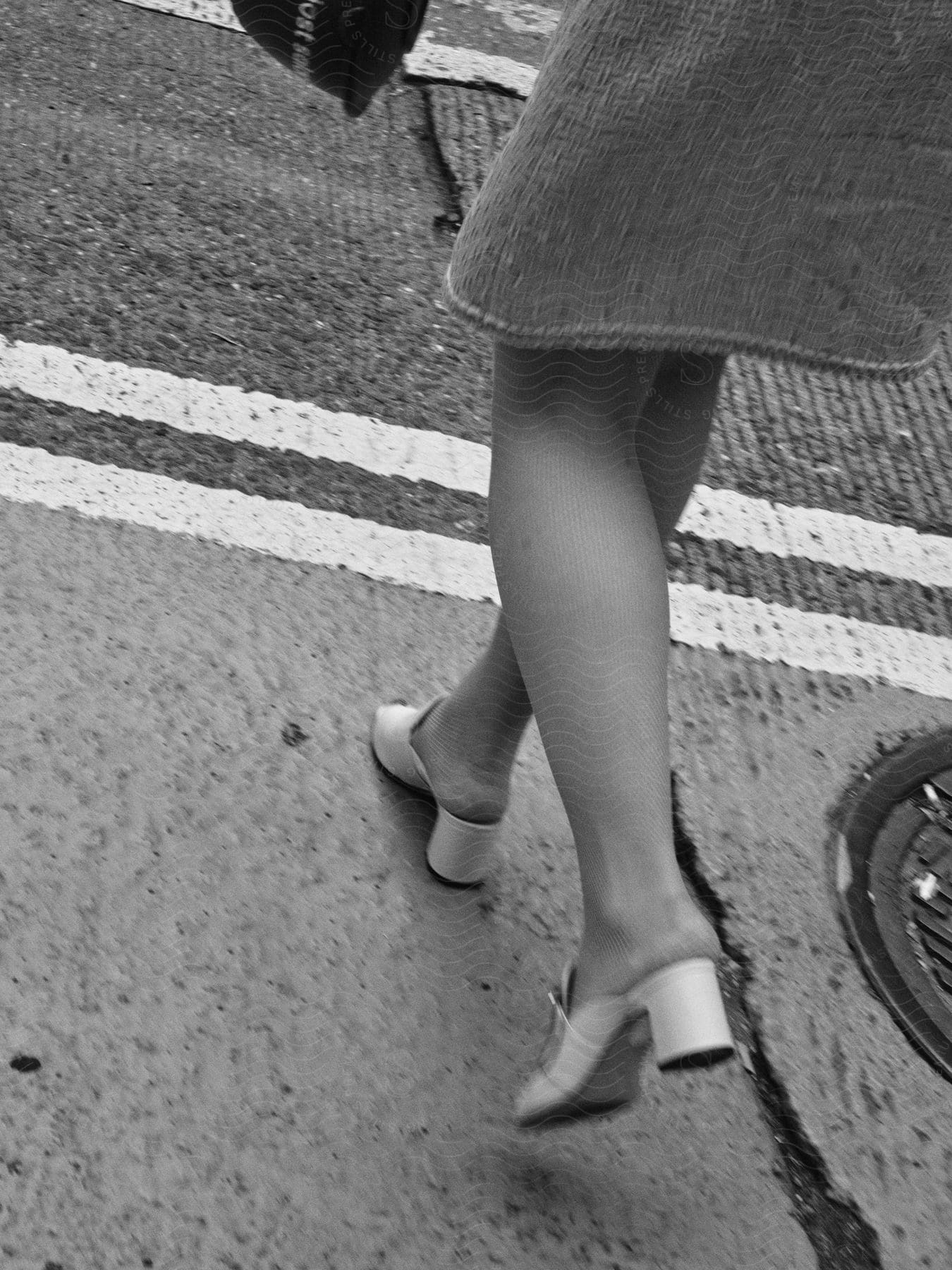 Woman wearing a skirt and heels walks into street.