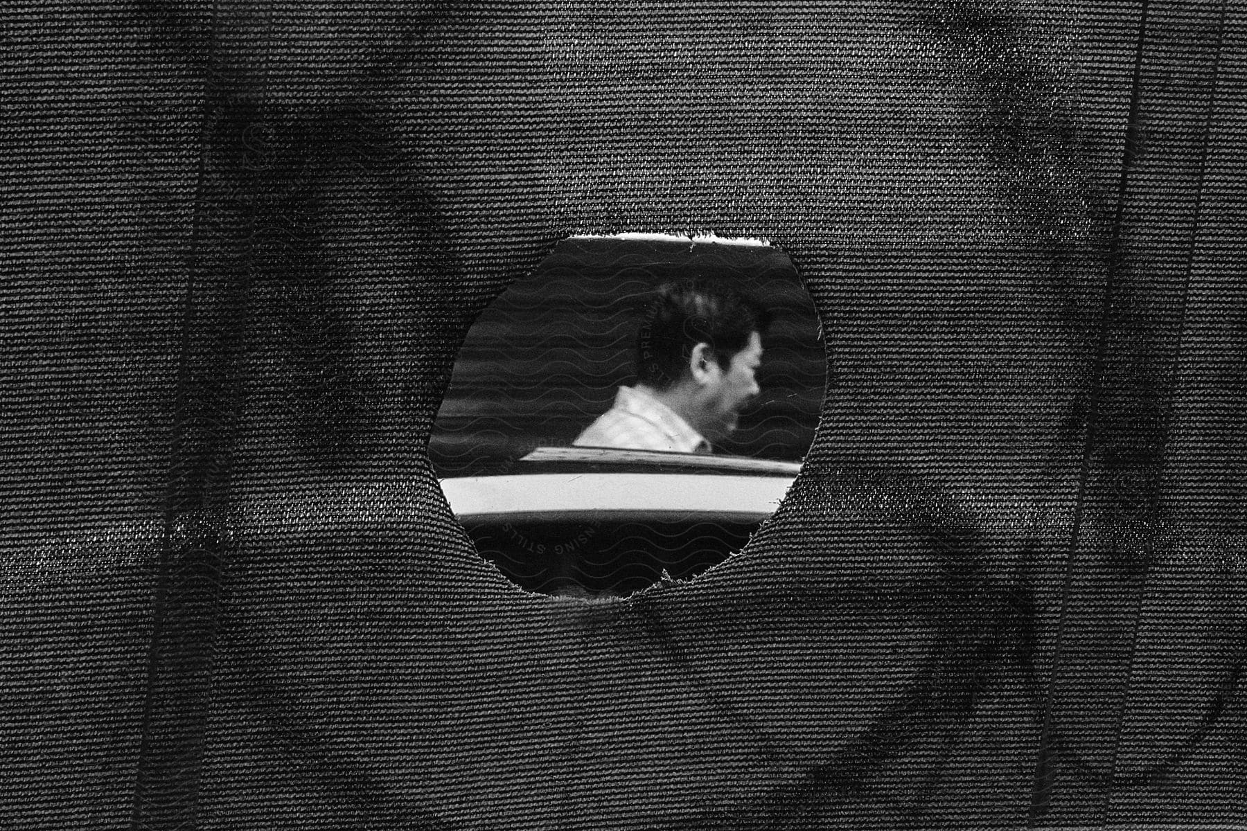 A portrait of a man through a hole in a screen fabric