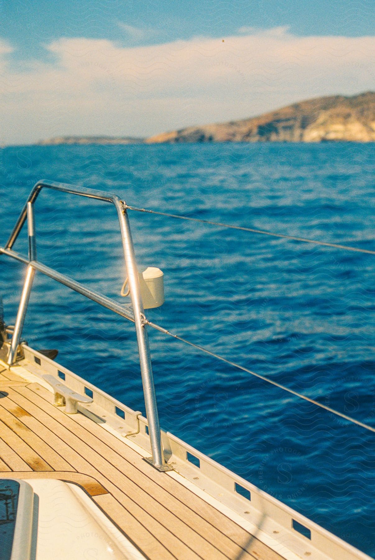 View from a boat of a buoy in the water and mountainous landforms along the coast