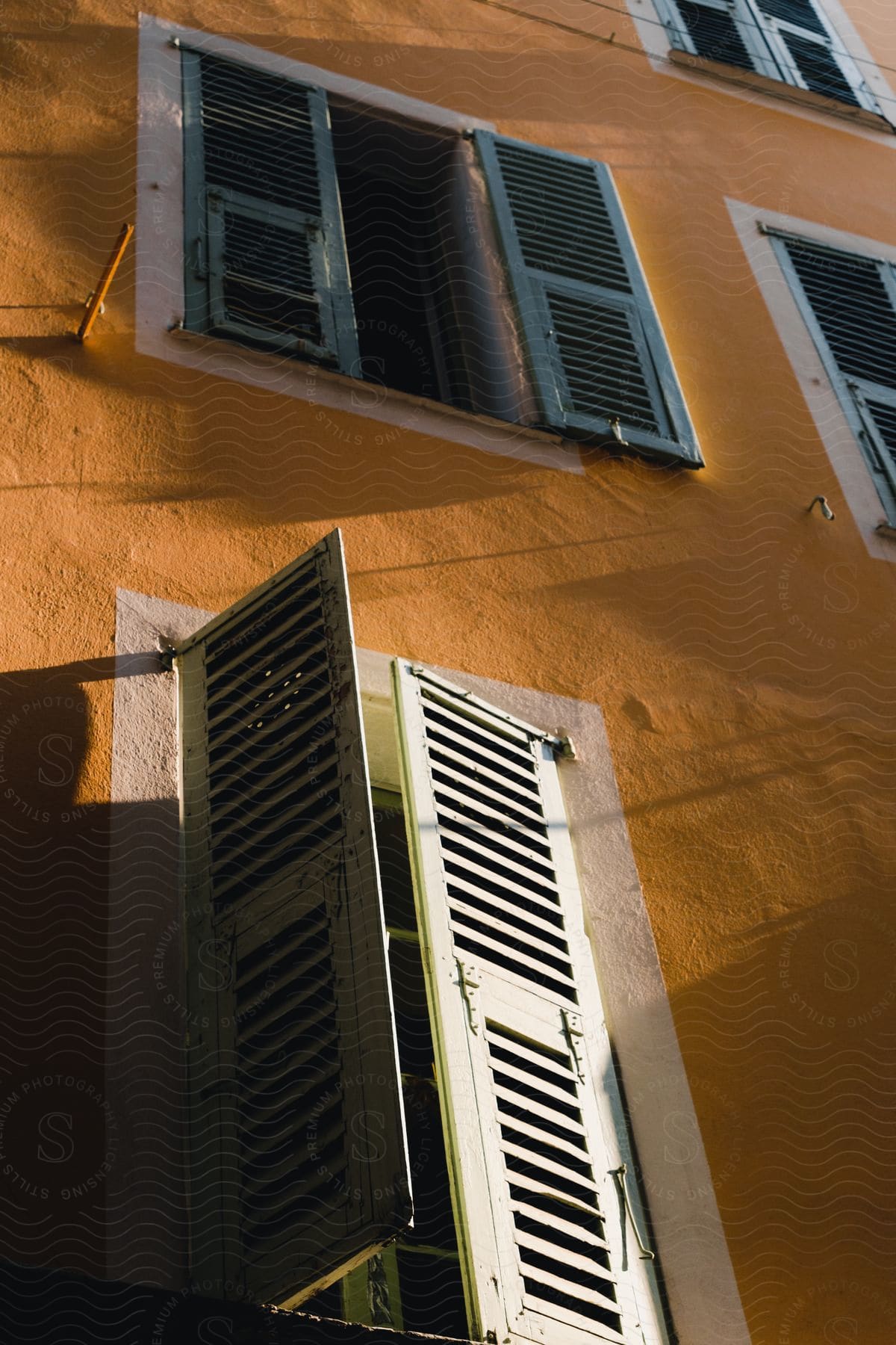 Shuttered windows in an old yellow building.