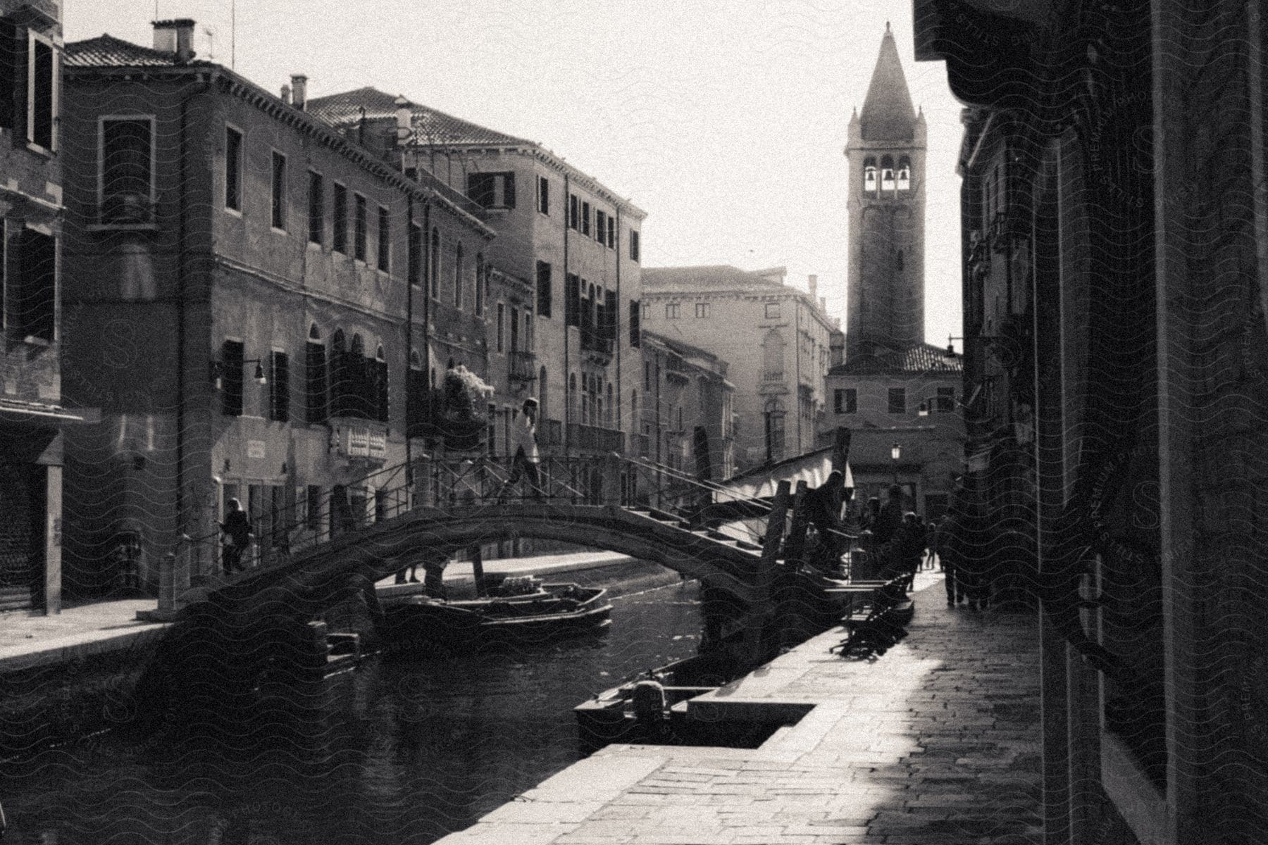 Stock photo of a picturesque retro city view features a charming canal running through the middle, with a person strolling on a bridge that connects both sides of the street, adding a nostalgic touch to the scene.