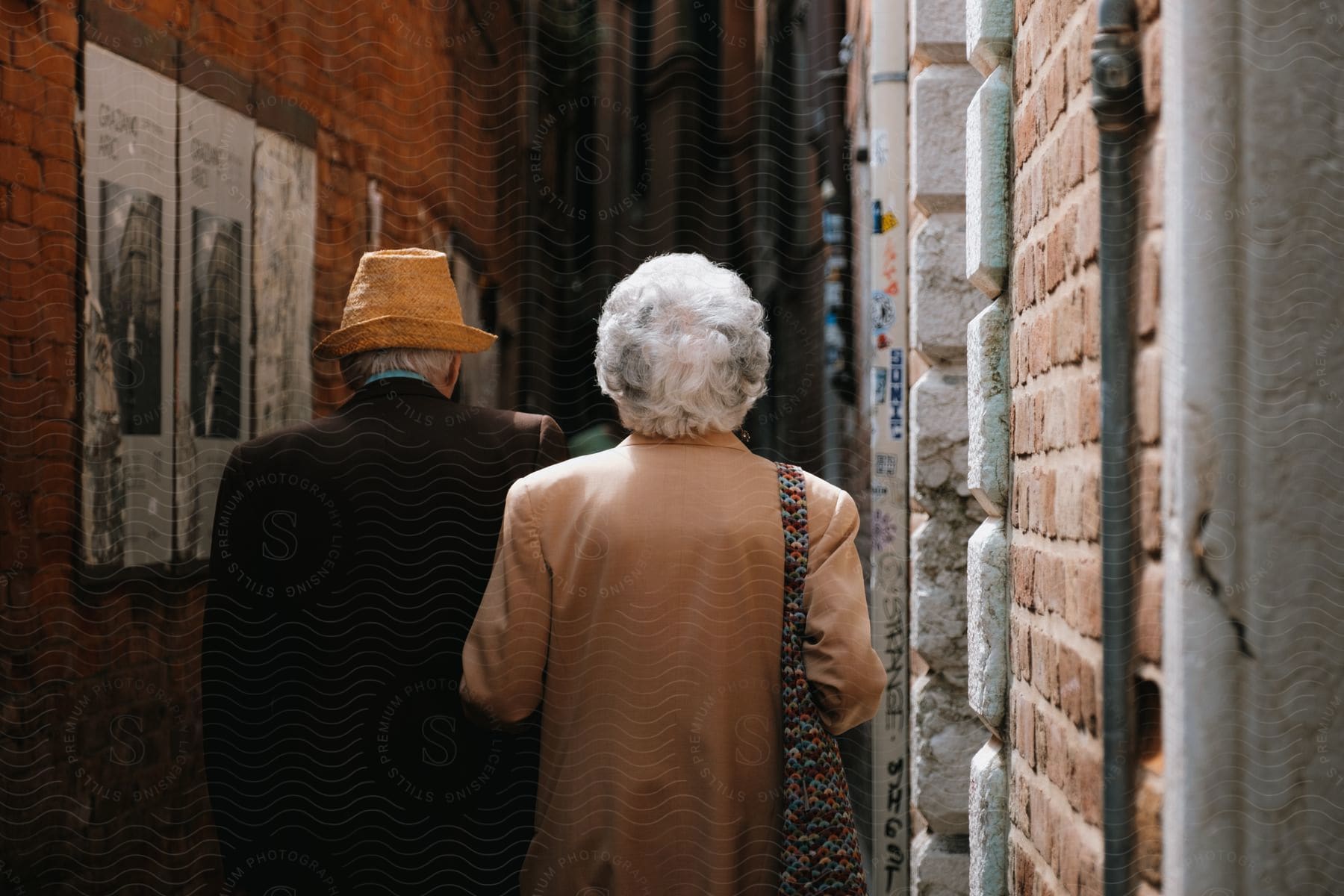 Couple walking arm in arm outdoors, in a narrow space between buildings