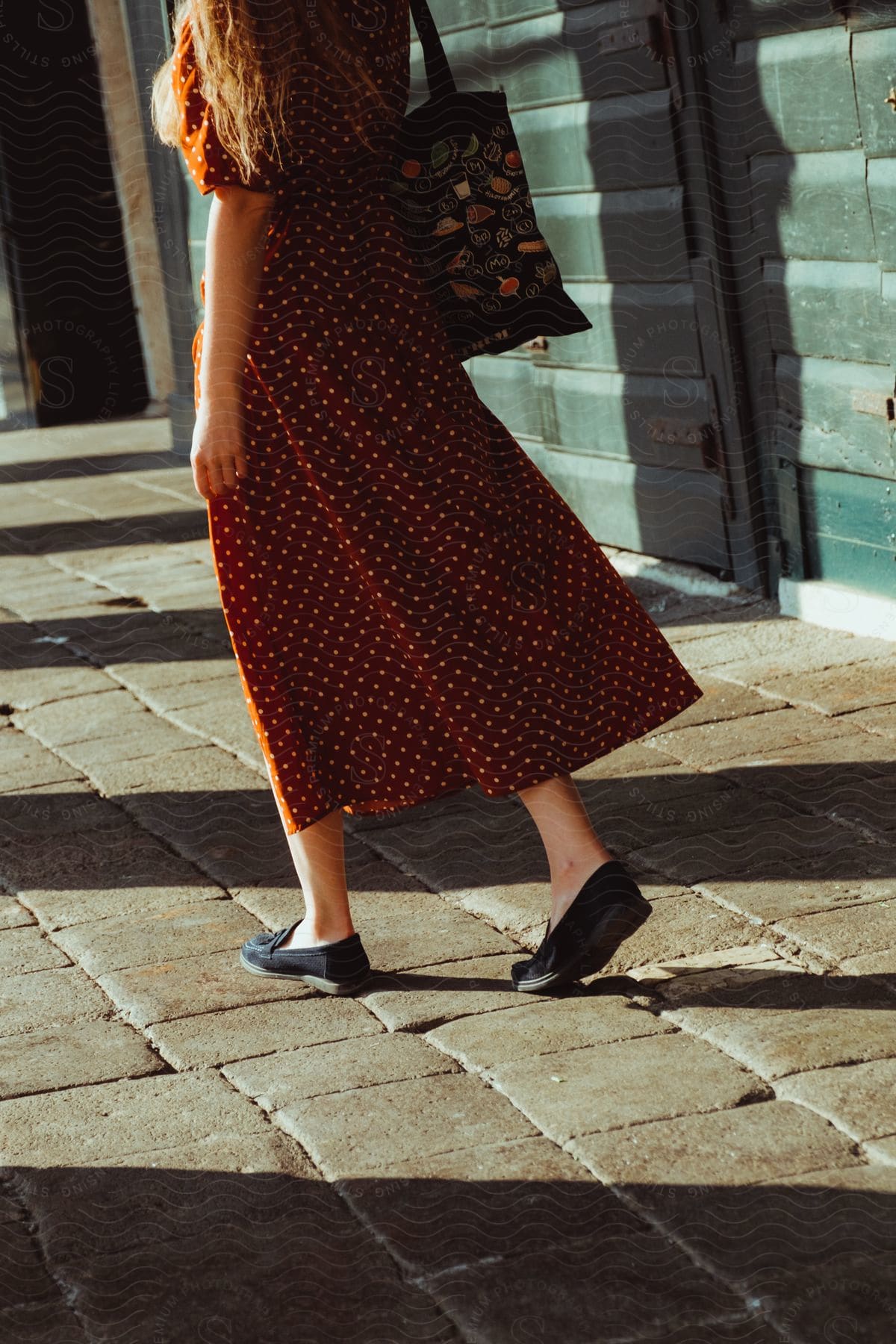 Woman walking in a red dress and a shoulder bag.